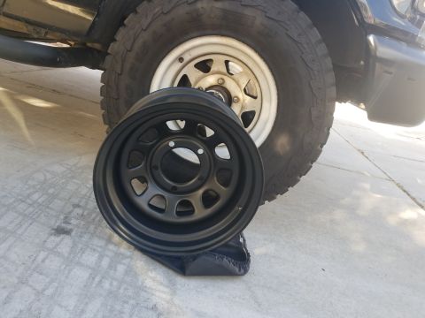 1993 Ford Bronco - A black aftermarket wheel is positioned in front of the tire and fender of a vehicle.