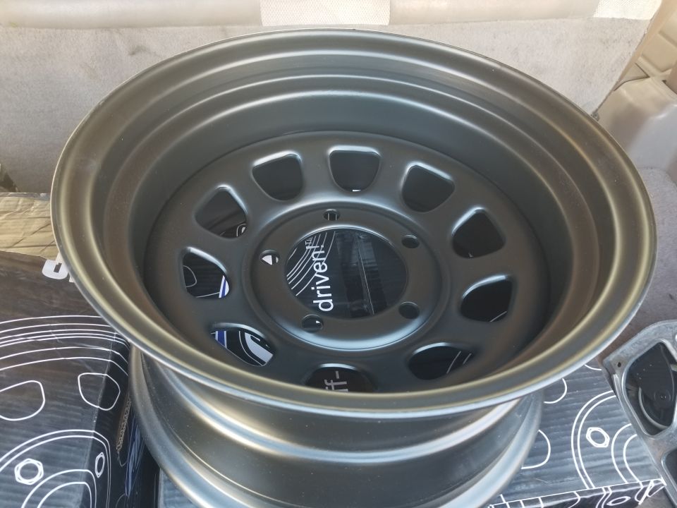 Aftermarket wheel with 'driven' logo on center cap, next to boxes