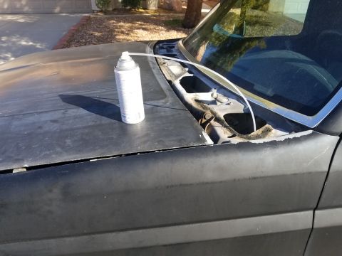 1993 Ford Bronco - A can of spray paint rests on the hood of a dark-colored vehicle, near the windshield cowl.