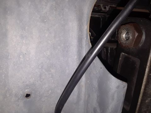 1985 Ford Bronco - Undercarriage view showing a metal panel, hose, and mechanical part.