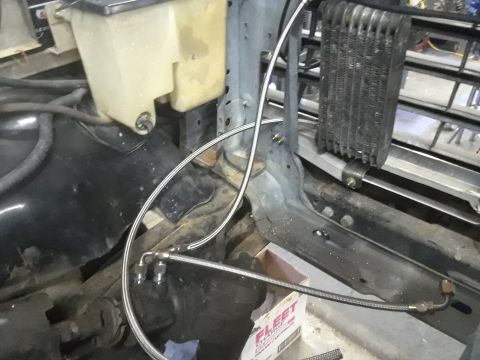 1985 Ford Bronco - Close-up view of engine bay components, including a fluid reservoir and oil cooler, with visible metal lines and a box labeled 'FLEET'.