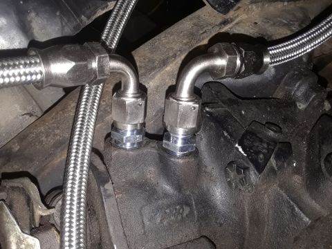 1985 Ford Bronco - Close-up view of braided hoses attached to an engine component, likely part of a fluid system.