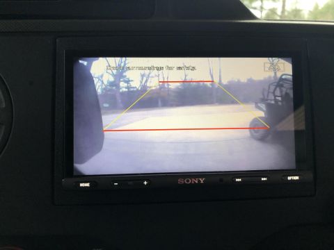 2010 Ford E250 - The backup camera displays a side-by-side vehicle in the distance, with guidelines on the screen.