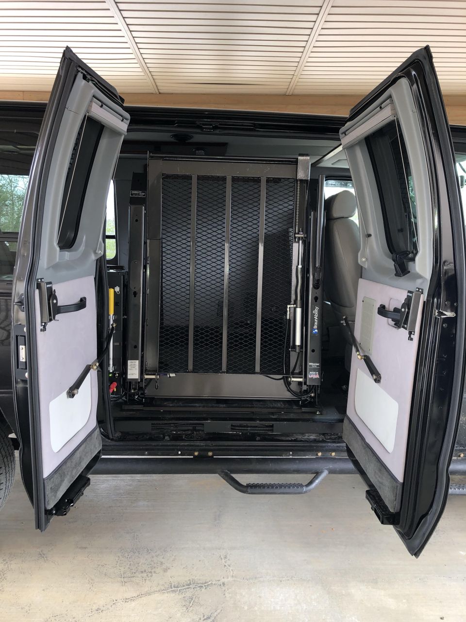 Van interior showing open rear doors and a deployed wheelchair lift mechanism