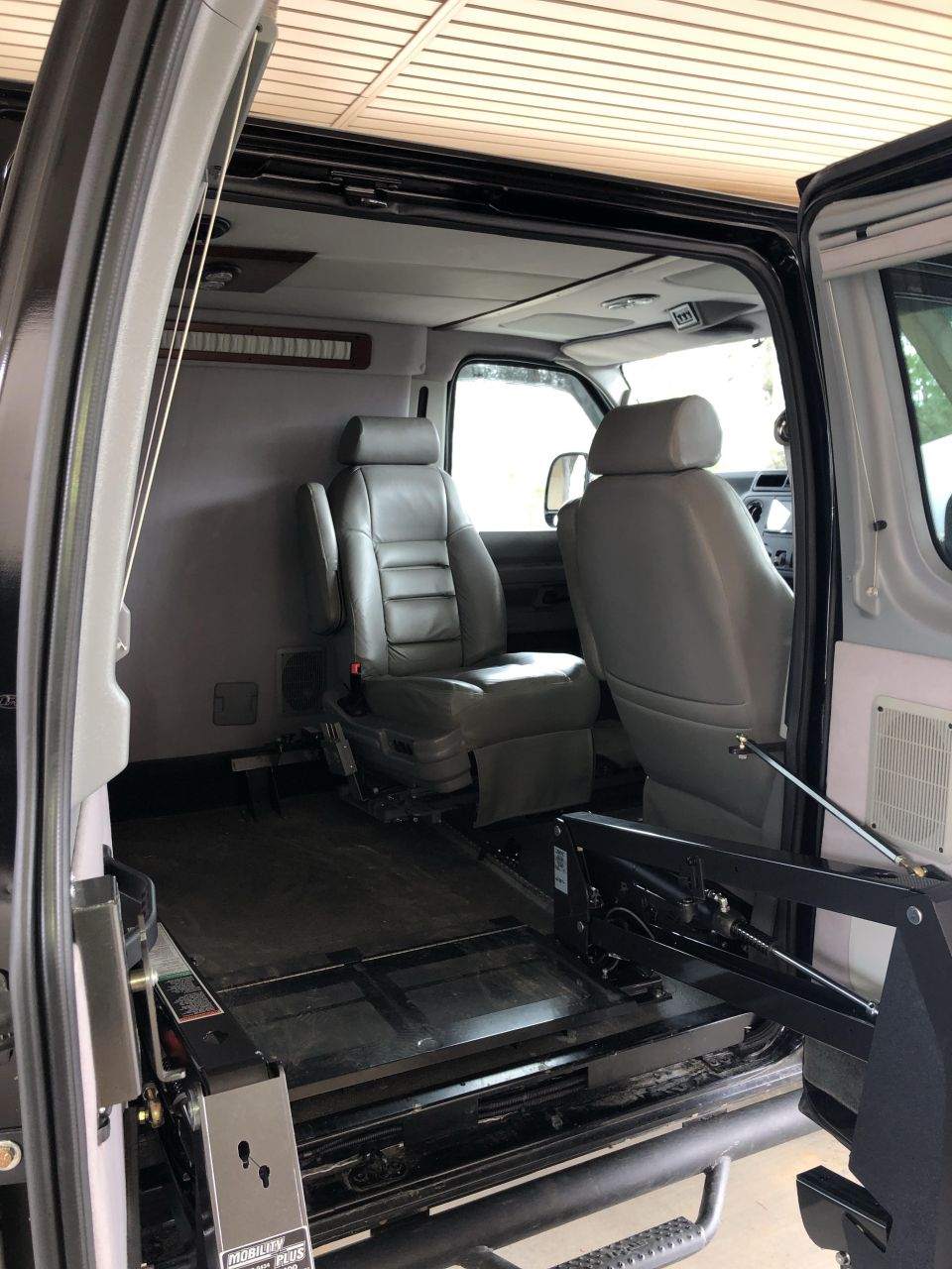 Interior of a van showing two rows of leather seats and a wheelchair lift mechanism