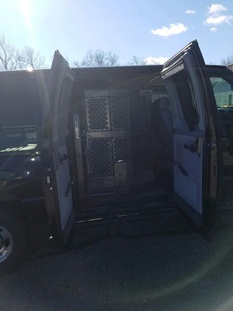 2010 Ford E250 - Interior view of a 2010 Ford E250 van, equipped with cargo partitions and open side doors.