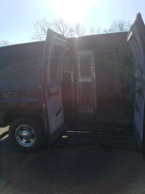 2010 Ford E250 - The side and rear doors of a 2010 Ford E250 van are open, revealing its utilitarian interior with metal grating.