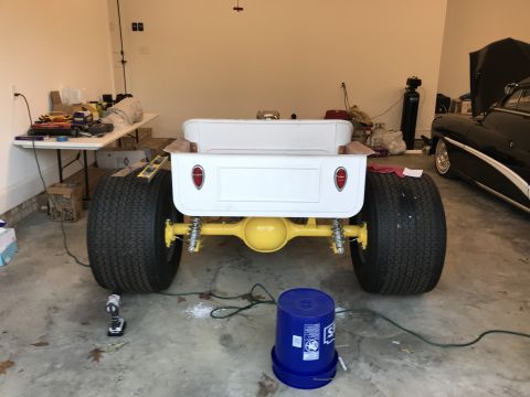1923 Ford Model T - Rear view of a custom hot rod pickup truck in a garage, with another car visible.