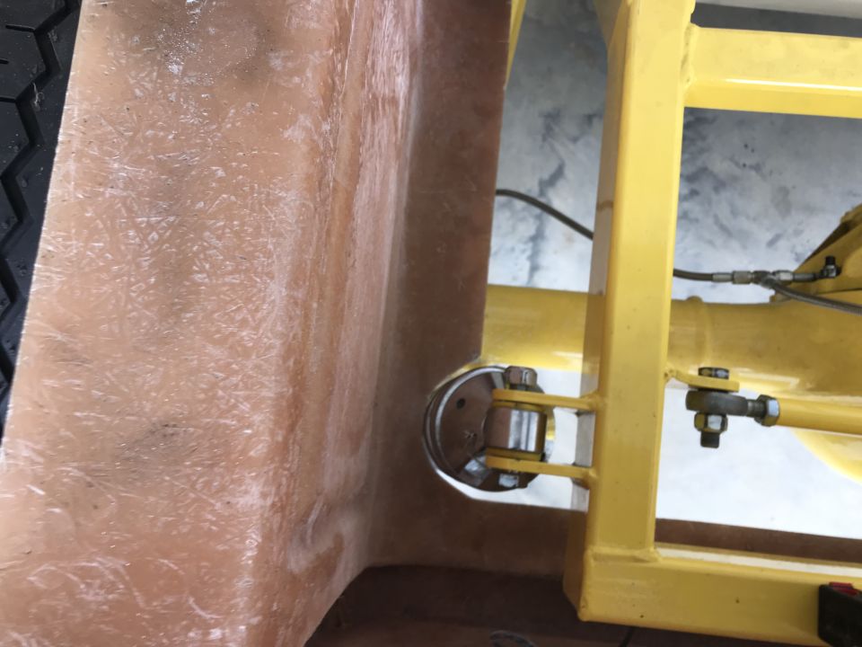 Close-up of a fiberglass body panel next to yellow chassis components with visible suspension parts