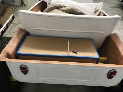 1923 Ford Model T - The rear of a white pickup truck bed is shown, filled with a large wooden box and other cargo, unidentifiable cargo.