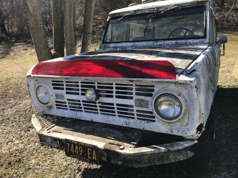 1967 Ford Bronco - Front view of a weathered 1967 Ford Bronco with a red stripe on the hood and Maryland plates.