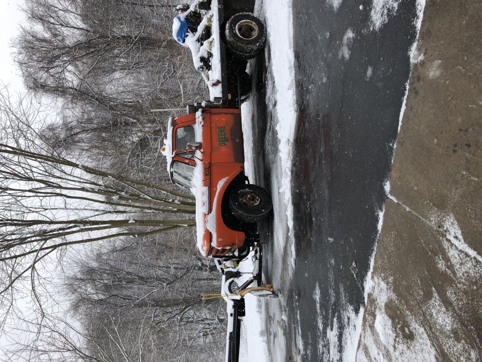 Orange truck with snow plow and "GREENS" text on door