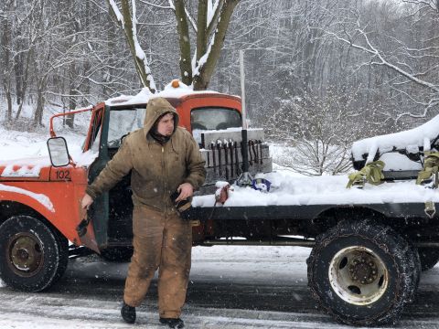 1961 Ford F-350 - A man stands by an orange truck in a snowy environment, with the number 102 visible on the door.