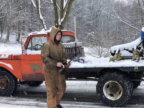 1961 Ford F-350 - A man stands next to an orange 1961 Ford F-350 flatbed truck during a snowfall.