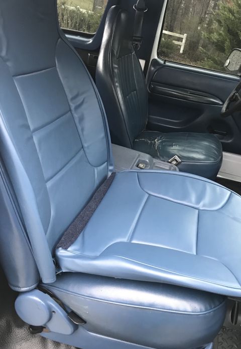 1995 Ford Bronco - Interior view of a 1995 Ford Bronco, highlighting the blue vinyl seats and the condition of the driver's seat.