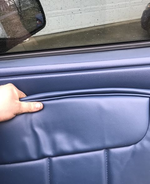 1995 Ford Bronco - Close-up of a blue interior door panel with a hand resting on it.