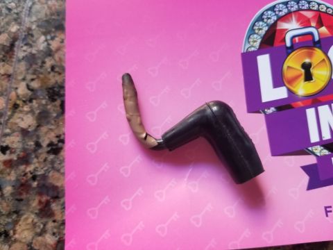 1993 Ford Bronco - A detached spark plug wire boot lies on a pink surface adorned with a key pattern.
