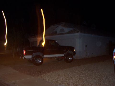 1992 Ford Bronco - A dark brown and white 1992 Ford Bronco is parked in a driveway at night, with light streaks visible in the background.
