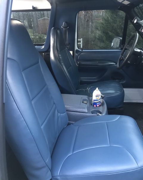 1995 Ford Bronco - Interior view of a vehicle, showing the front seats, dashboard, and steering wheel. A can of air freshener is in the cup holder.