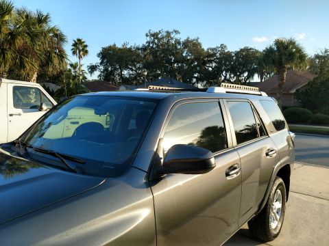 2018 Toyota 4Runner - Gray Toyota 4Runner with a roof rack is parked next to a white van.