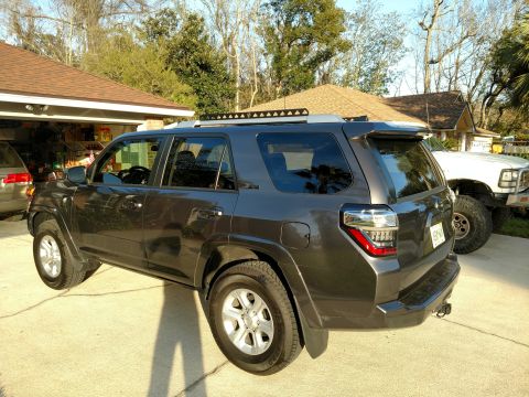 2018 Toyota 4Runner - Dark gray SUV parked in a driveway next to a white truck.