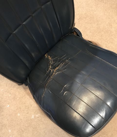 1995 Ford Bronco - This blue vinyl car seat shows significant wear and tear on the driver's side cushion, with visible rips and damage.