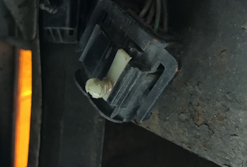 Close-up of a black electrical connector with a white plastic piece and wires. A yellow light is visible on the left