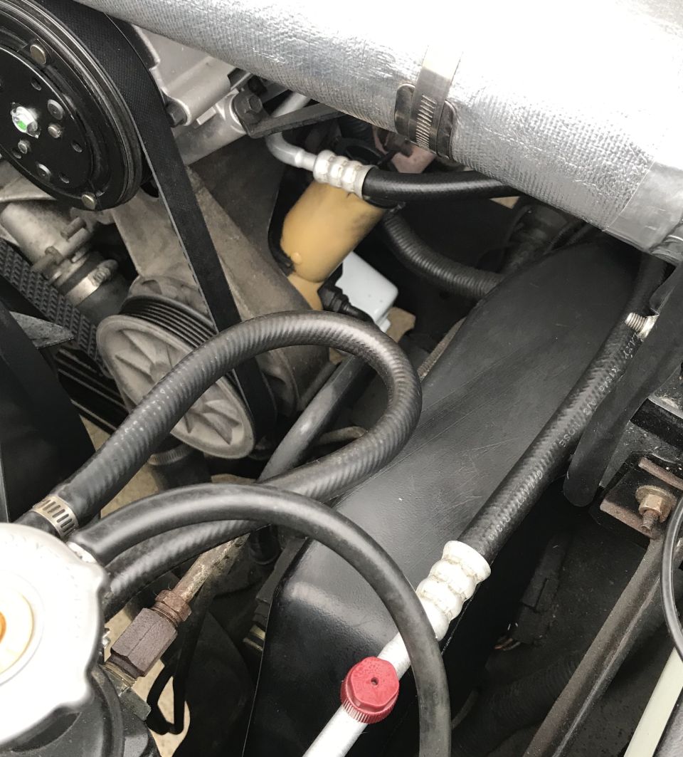 Engine bay hoses, belts, and pulleys. Includes AC compressor and part of the radiator