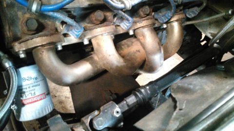 1978 Ford Bronco - Close-up view of engine components including the exhaust manifold and an oil filter.