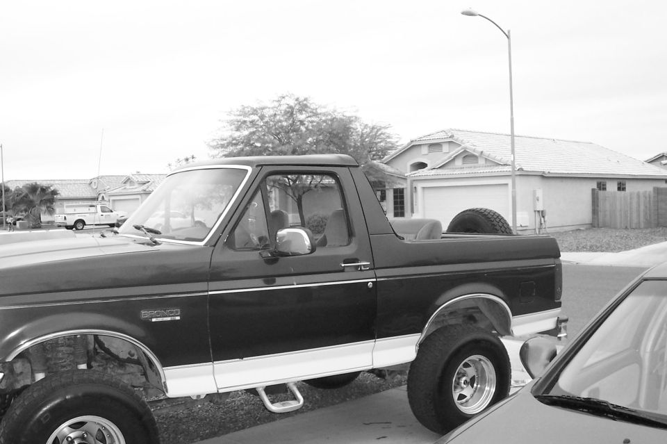 Topless lifted Ford Bronco parked in a suburban street, black-and-white photo