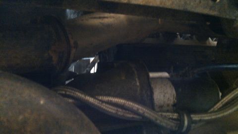 1978 Ford Bronco - Close-up view of a vehicle's starter motor and exhaust pipe assembly.