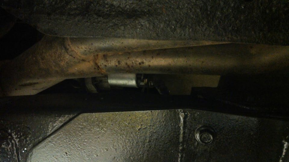 Underside view of vehicle frame and exhaust pipe with a Supermotors.net watermark