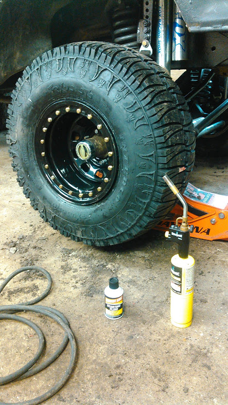 1978 Ford Bronco - A close-up of an off-road tire and wheel assembly, with tools nearby.