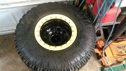 1978 Ford Bronco - Off-road tire and wheel assembly shown in a garage setting with tools.
