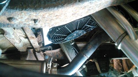 1978 Ford Bronco - This photo shows an electric fan and exhaust system components from underneath a vehicle.