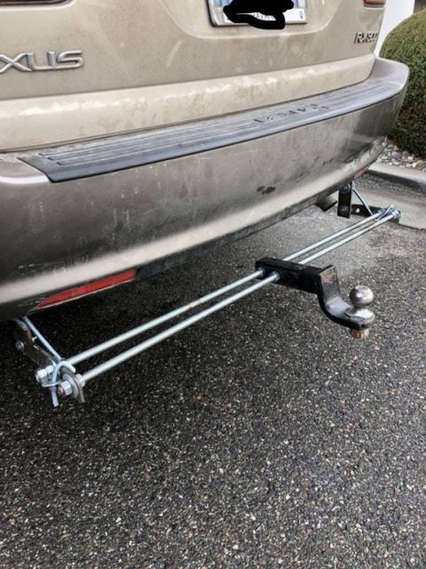 1992 Ford Bronco - The rear of a tan SUV is shown with a trailer hitch assembly mounted to the bumper.