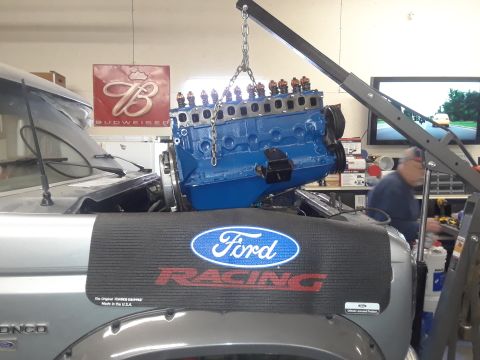 1985 Ford Bronco - Engine installation in progress on a 1985 Ford Bronco, with a Ford Racing fender cover visible.