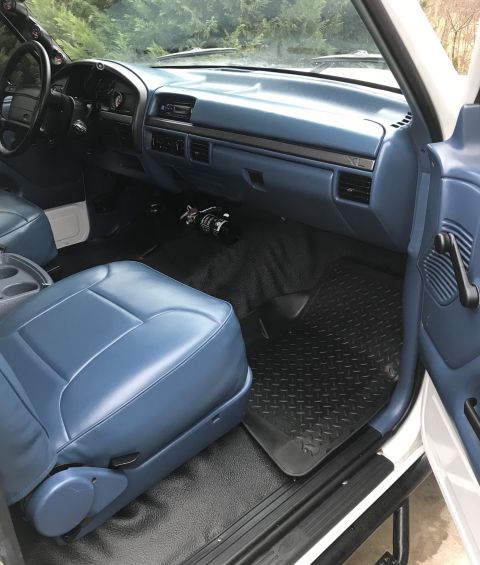 1995 Ford Bronco - The interior of a 1995 Ford Bronco features blue vinyl seats, a blue dashboard, and black floor mats.