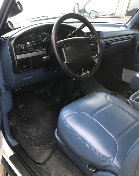 1995 Ford Bronco - The interior of this truck features blue vinyl seats and a dashboard with visible gauges and air vents.