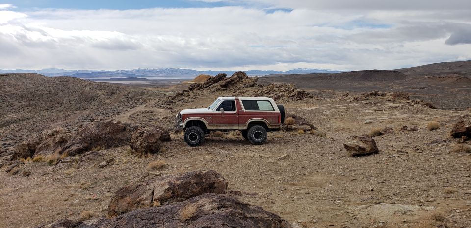 Red and white 1981 Ford Bronco parked on a rocky, arid landscape