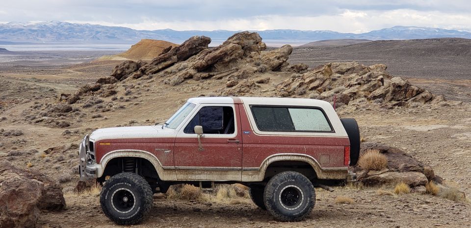 Side view of a red and white Ford Bronco parked in a rocky, desert landscape