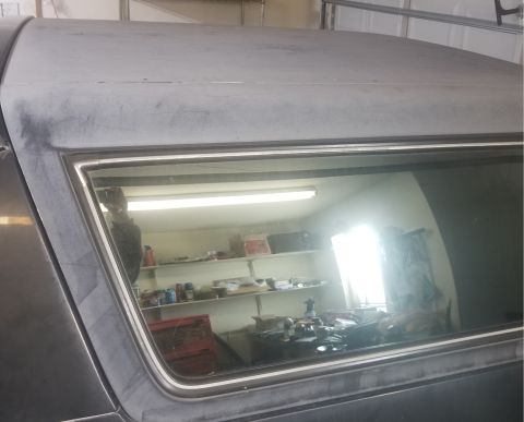 1993 Ford Bronco - The reflection in the window shows a cluttered garage interior with shelves stocked with various items.