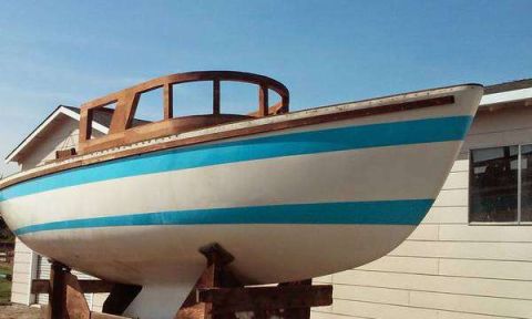 1991 Ford Bronco - A boat with a wooden cabin structure sits on a trailer in front of a house.