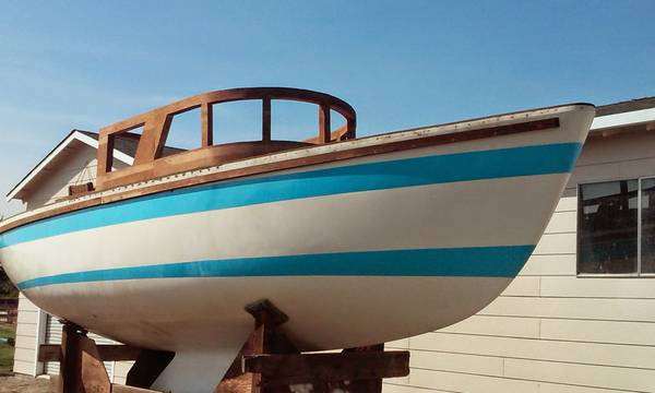 Boat with blue stripes on a trailer, next to a house