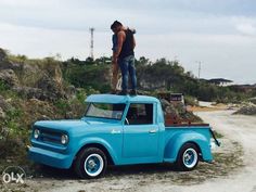 1991 Ford Bronco - A light blue pickup truck is parked outdoors with two people on its roof.