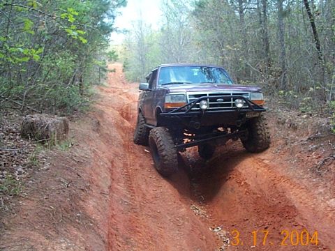 1986 Ford Bronco - This modified Ford Bronco tackles a challenging off-road trail with steep inclines and ruts.