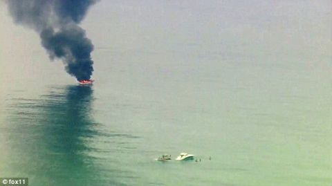 1991 Ford Bronco - A boat engulfed in flames and emitting thick black smoke is seen in the water, with another vessel nearby.