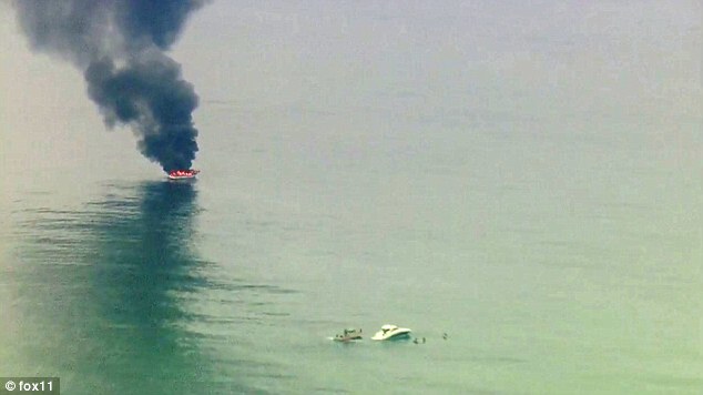 Boat on fire with black smoke billowing, another boat nearby