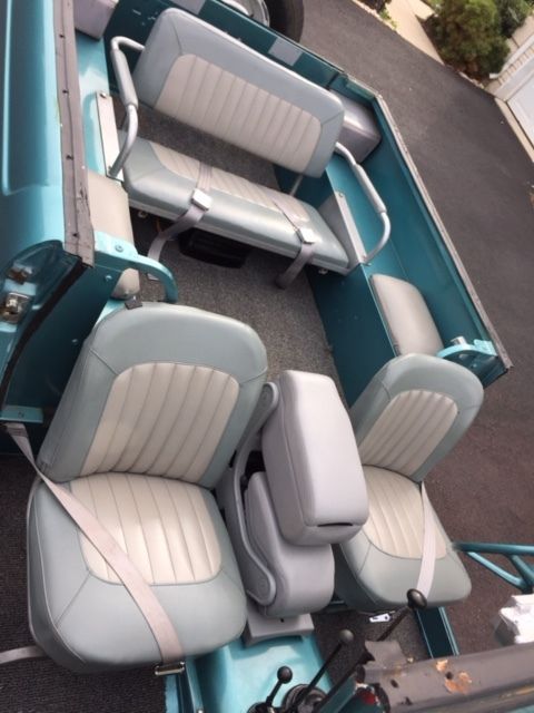 1991 Ford Bronco - The interior of a teal SUV is shown, light blue and white upholstered seats with seatbelts.