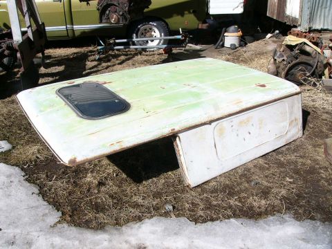 1991 Ford Bronco - A detached green and white Ford Bronco hardtop with a skylight is shown outdoors, with another vehicle and engine parts in the background.